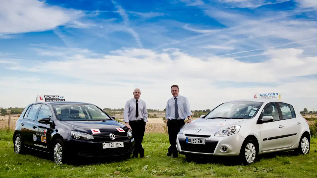 Two professional driving school instructors discussing road safety and traffic rules next to a training car, focus on student education.