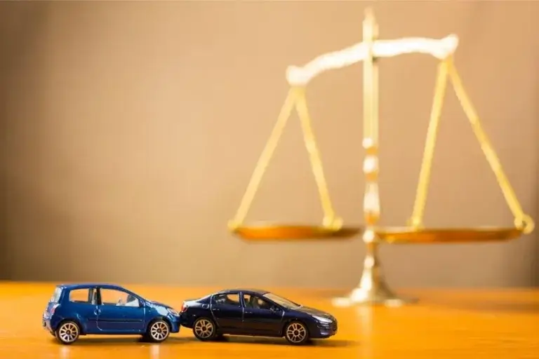 Two toy cars collided in front of a justice scale, symbolizing car accident liability claims