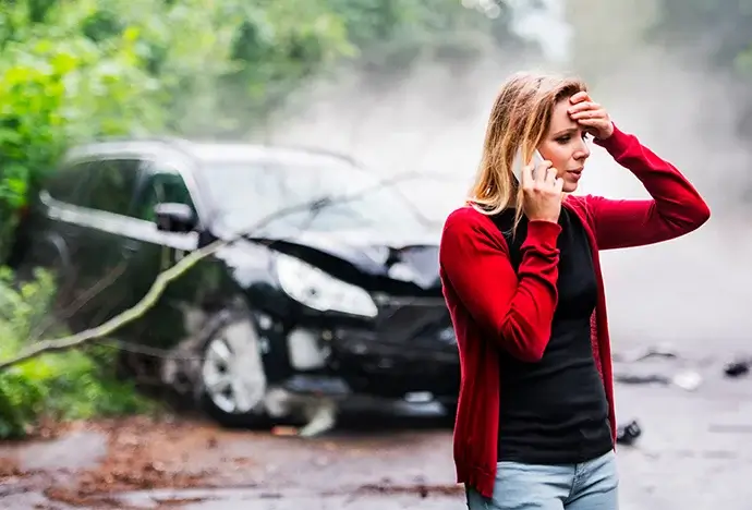 Woman calling a car accident lawyer after a crash on a rainy road